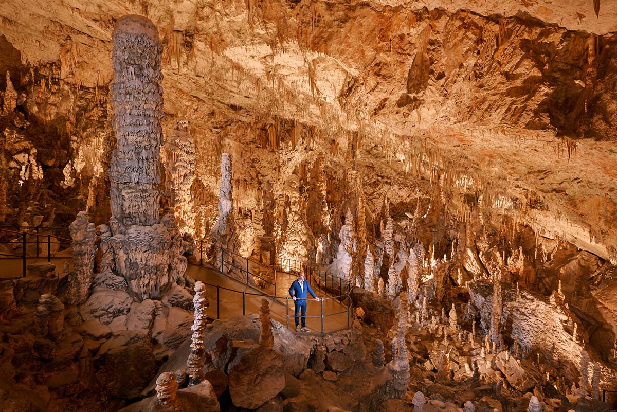 Un visitatore in una grotta con molte stalattiti.