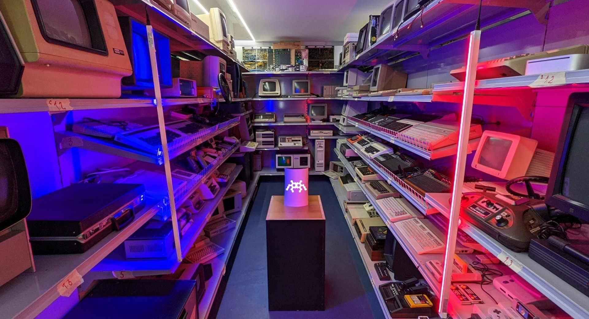 Shelves with retro computers, lit with pink light.
