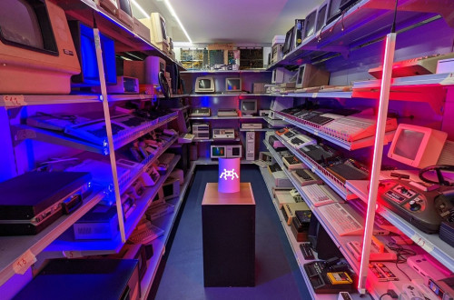 Shelves with retro computers, lit with pink light.