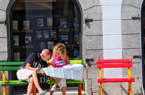 Dva turista gledata zemljevid in sedita na klopci v centru Ljubljane.