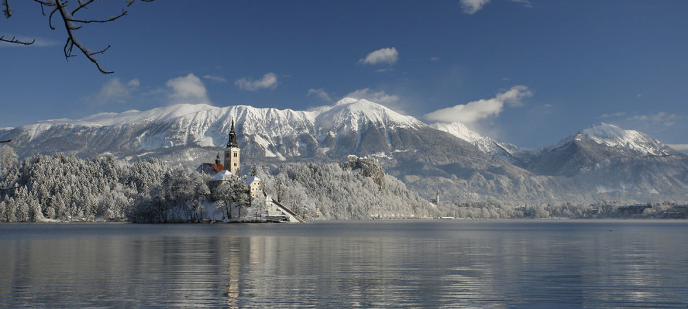 Blejski otok pozimi. V ozadju zasnežene gore.