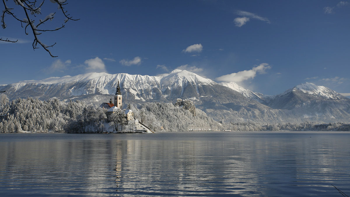 Blejski otok pozimi. V ozadju zasnežene gore.