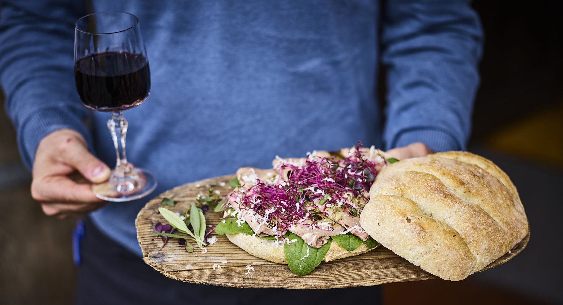 Goveji jezik, kruh na deski. Na levi strani kozarec vina.