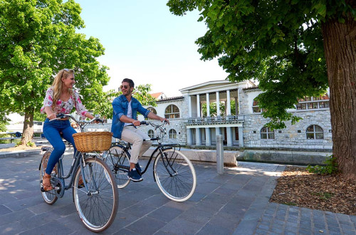 Kolesarja ob Ljubljanici. Za njima Plečnikova glavna tržnica.