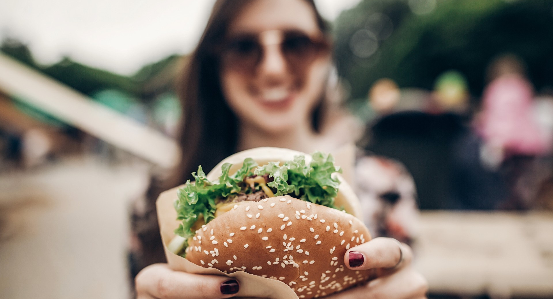 smiling girl holding a hamburger in her hands