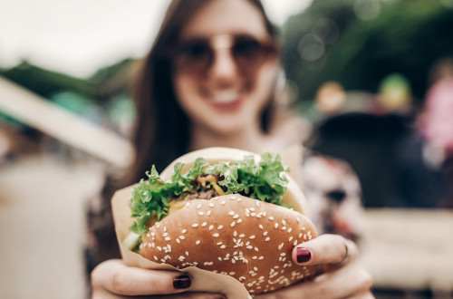 smiling girl holding a hamburger in her hands